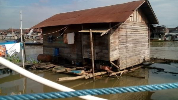 banner bagaimana bangunan rumah adat di daerah pinggiran sungai